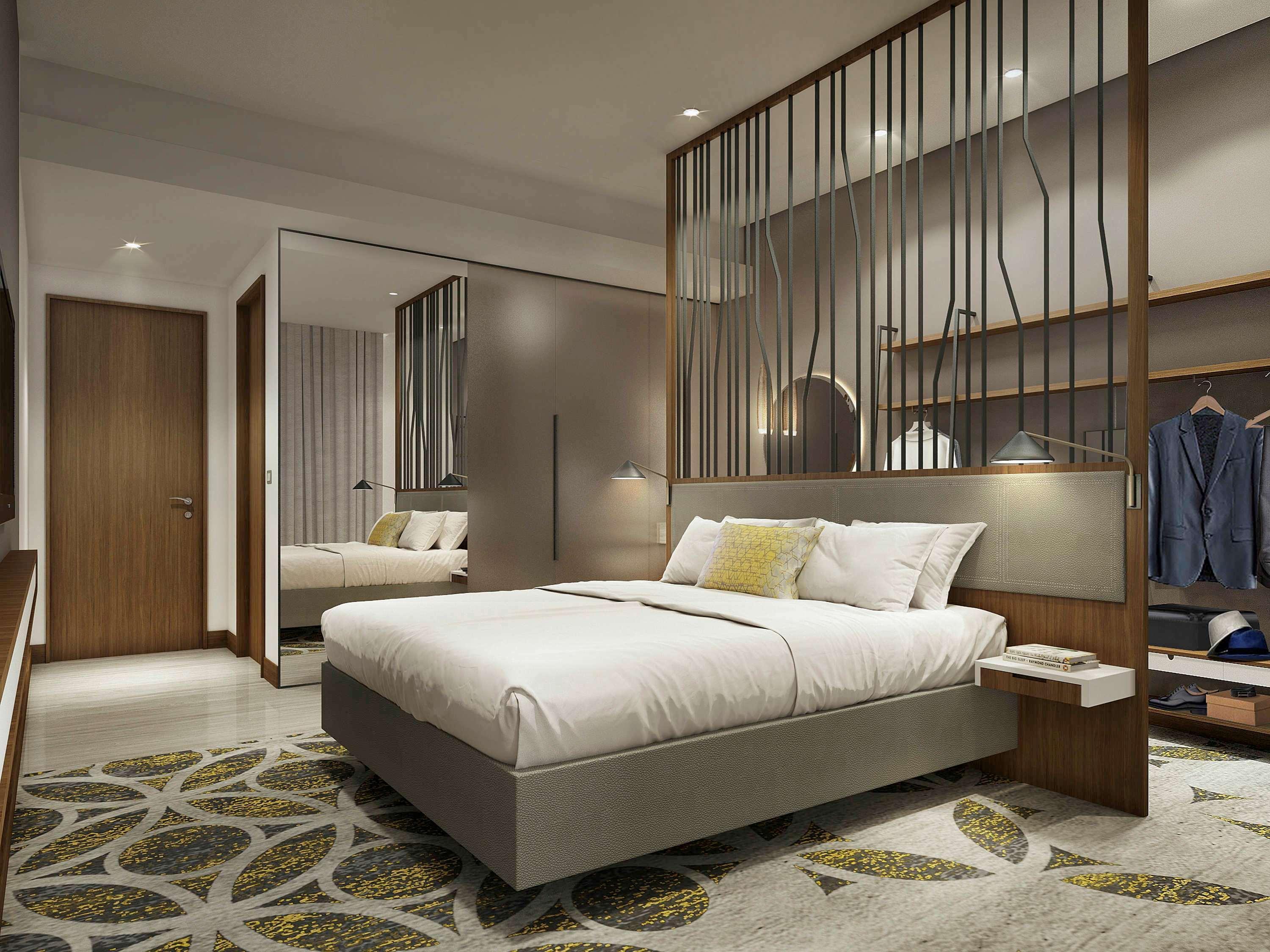 Grand Mercure Dubai City Exterior photo The photo shows a modern hotel room featuring a neatly made bed with white linens and a decorative pillow. The room has a stylish wooden partition that separates the sleeping area from the rest of the space. There are bedside tables on either side of