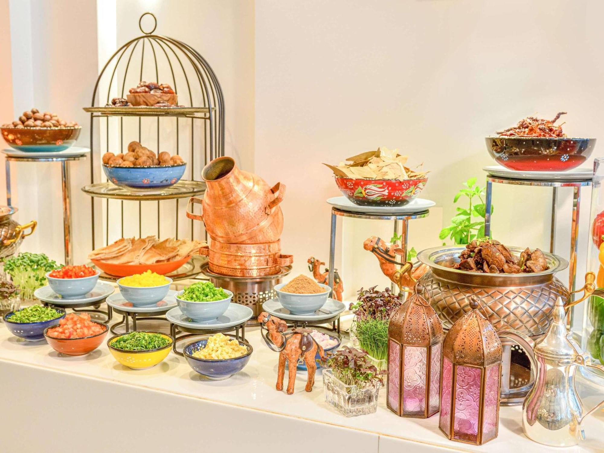 Grand Mercure Dubai City Exterior photo The photo displays a vibrant and elaborate buffet setup featuring a variety of dishes. On one side, there's a decorative metal stand with several tiers holding different types of foods, likely including cooked meats and other savory items. 

In the f